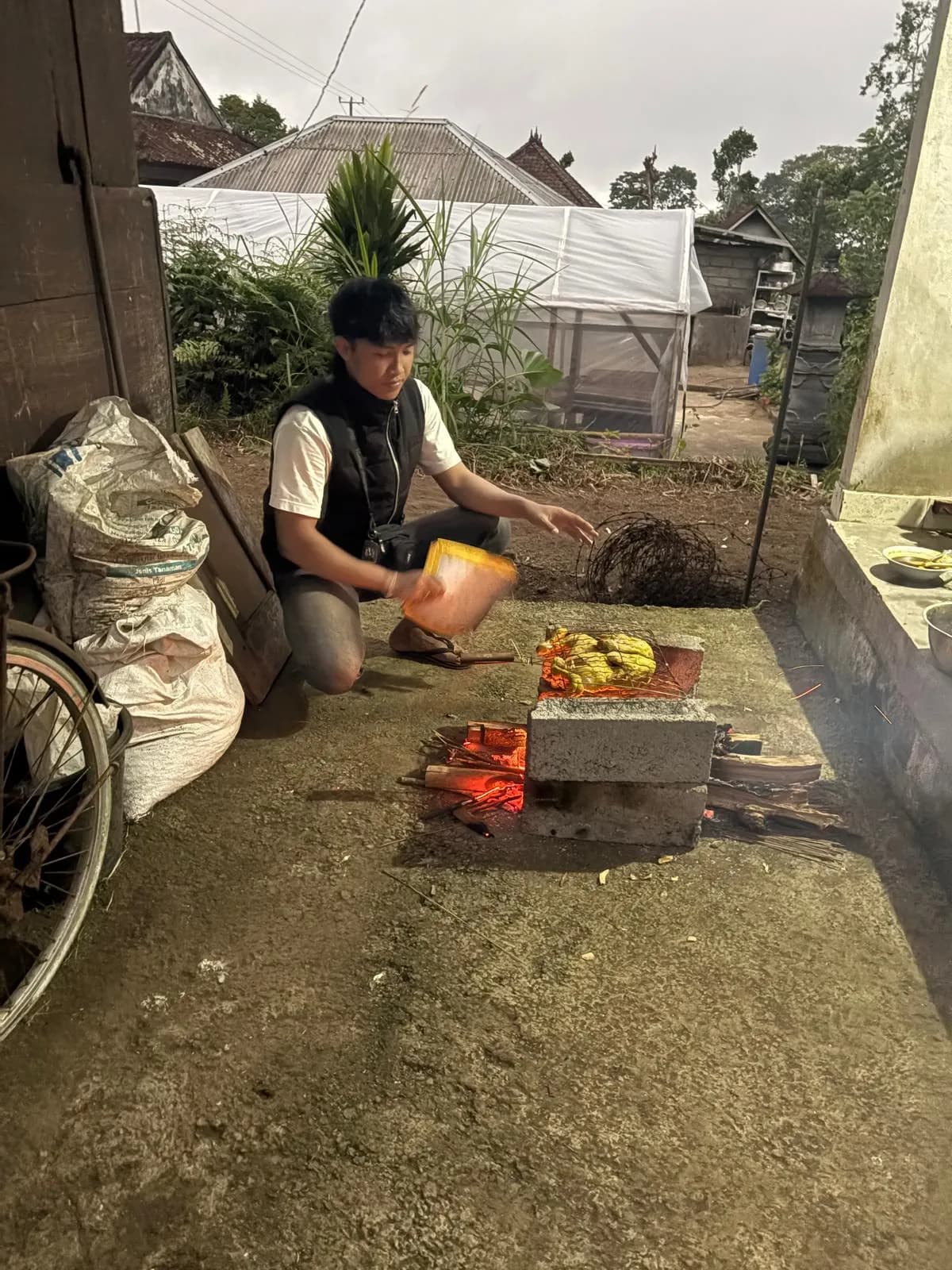 Grilling marinated chicken over a wood fire in the yard at dusk