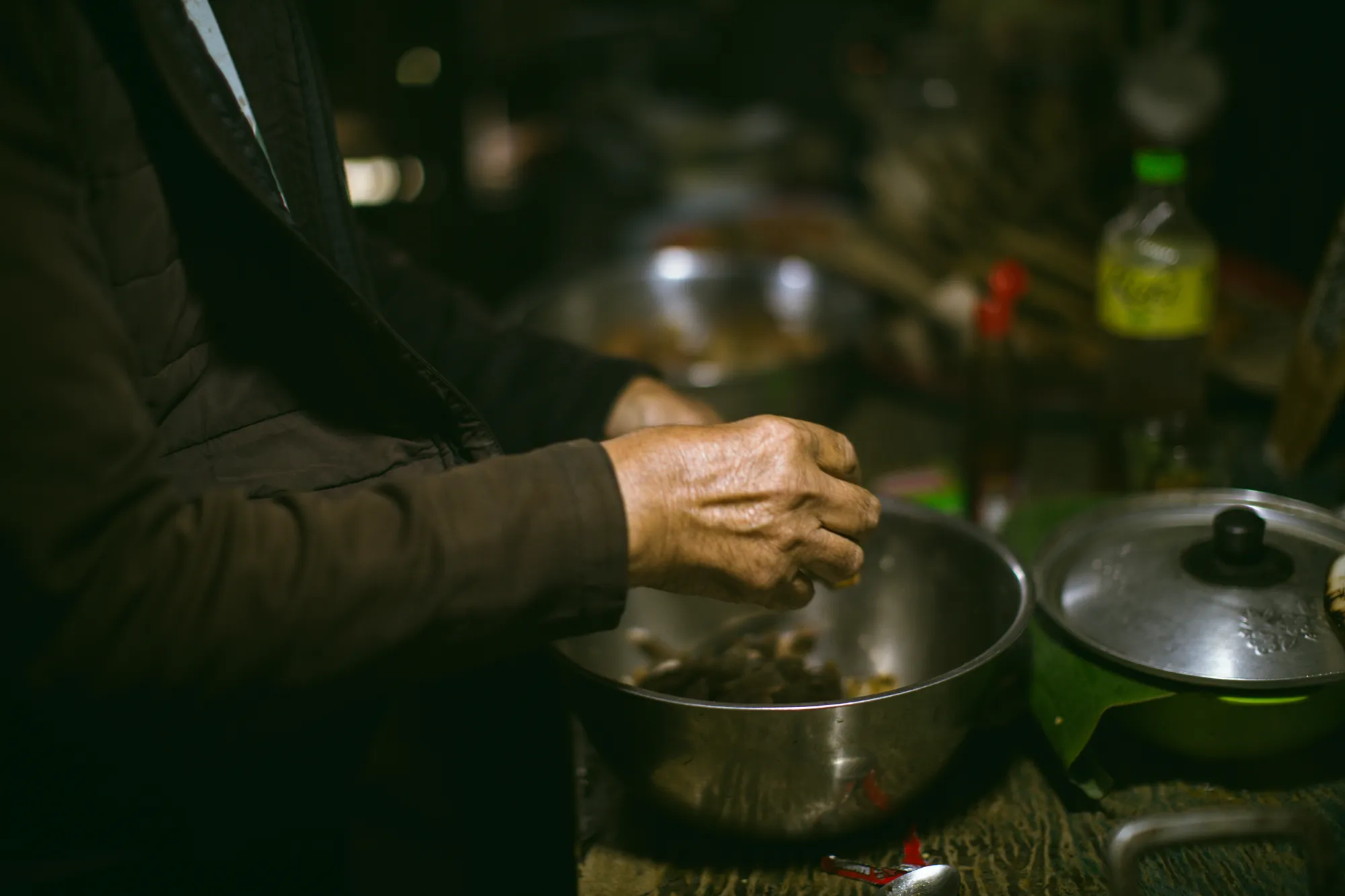 Hands at work over a steel bowl in the wood-fired kitchen